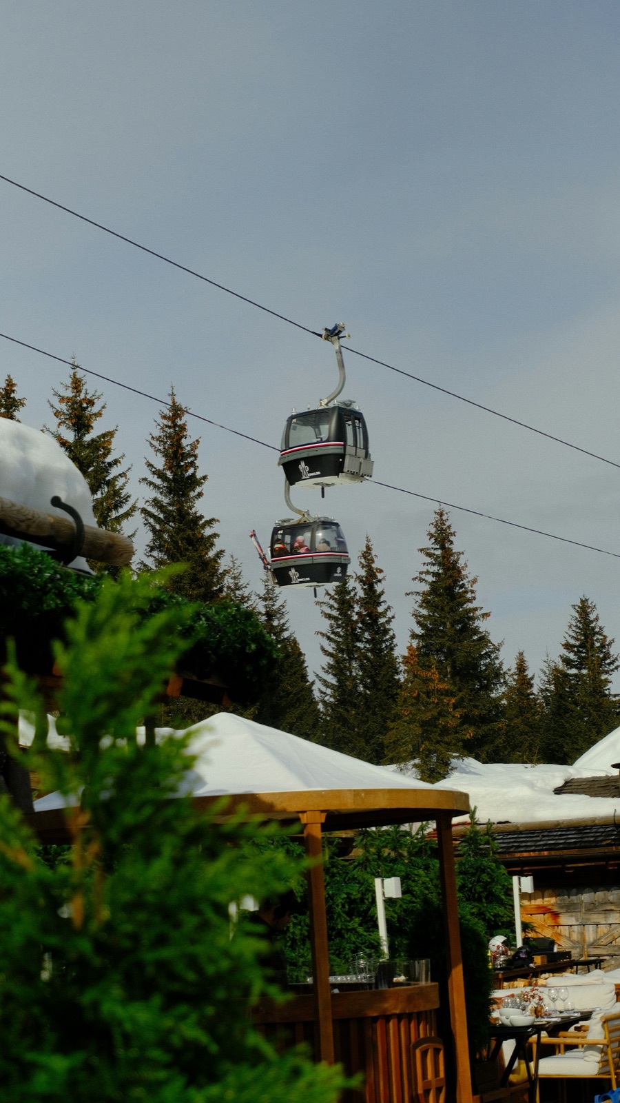 Gondolas above snowy fir trees and buildings in Courchevel 1850, France.