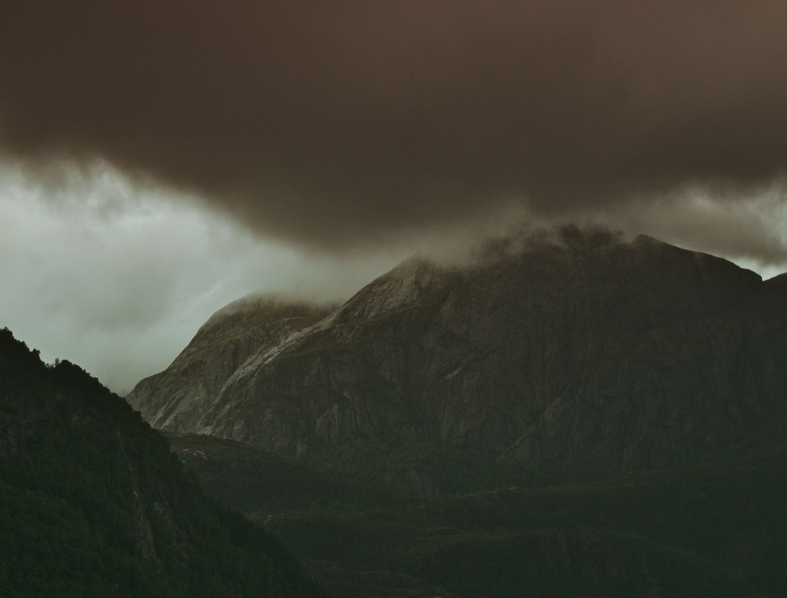 Dark green mountains near Dale i Sunnfjord beneath low cloud in Norway.